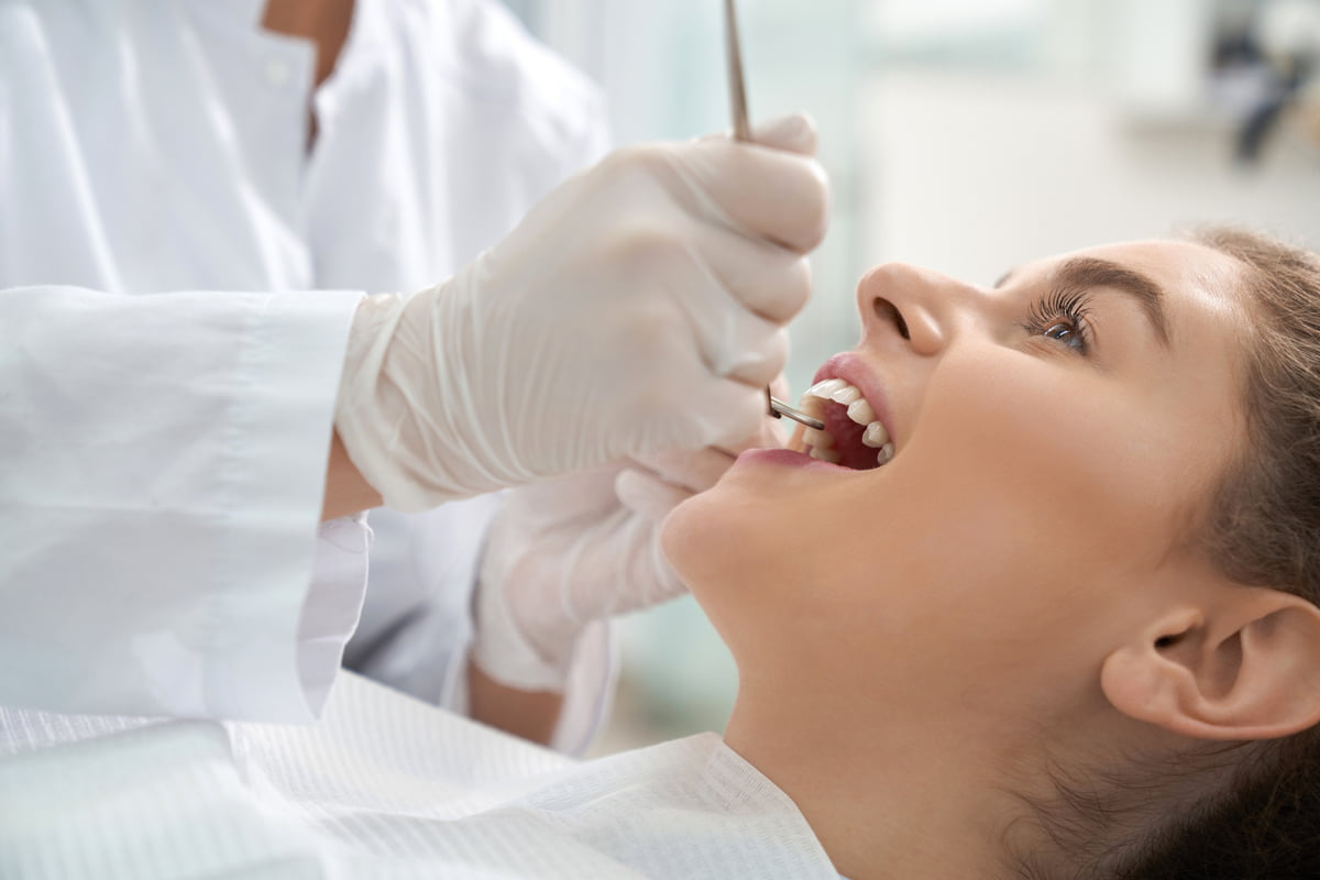 Woman receiving a dental examination while discussing oral health conditions with a dentist
