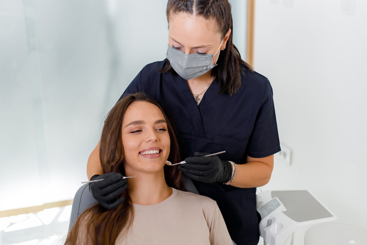 Dentist performing a routine dental check-up on a smiling patient during a long-term oral health consultation