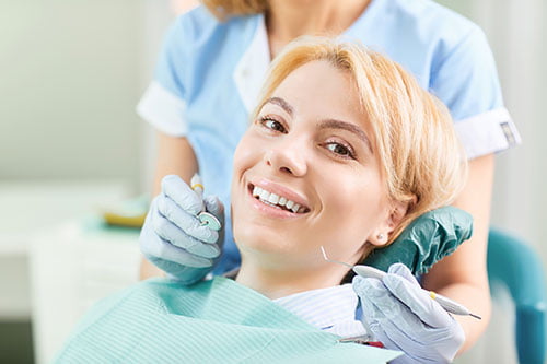 Dentist checking a patient's teeth during a follow-up visit after professional teeth whitening treatment