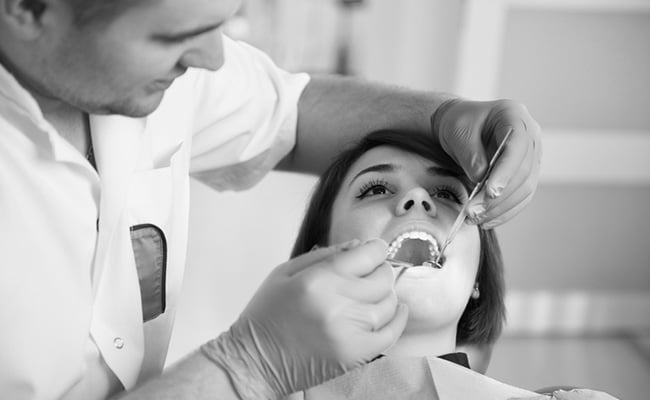 Dentist examining and treating a patient with a broken tooth in a modern dental clinic.