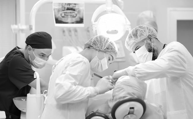 Dental surgeon and assistant performing a surgical procedure in a modern dental clinic.