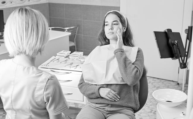 Patient experiencing severe tooth pain before receiving emergency dental treatment at a dental clinic.
