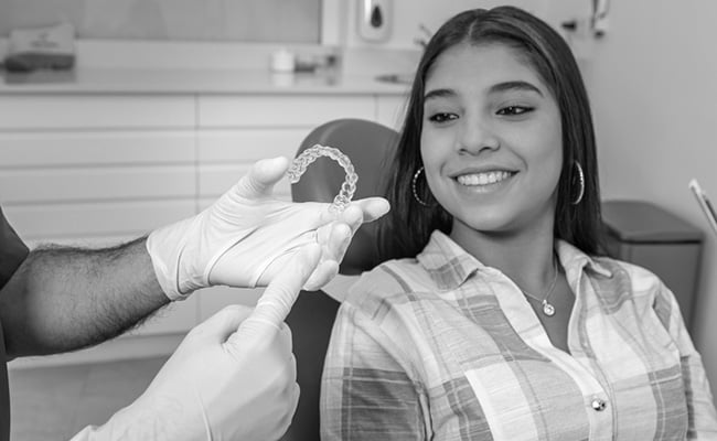 Dentist showing clear Invisalign aligners while discussing orthodontic treatment options with a patient.