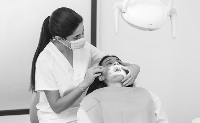 Dentist performing an oral cancer screening examination during a routine dental checkup in a modern clinic.