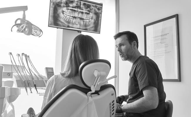 Dentist reviewing a digital dental X-ray with a patient while discussing root canal treatment options.