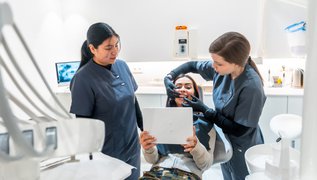 Dentist showing teeth whitening results to a smiling patient in Canada