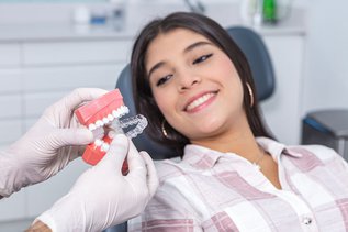 Dentist showing Invisalign clear aligners during a consultation in Maple, ON