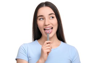 Woman using a tongue scraper as part of her daily oral hygiene routine in a bathroom